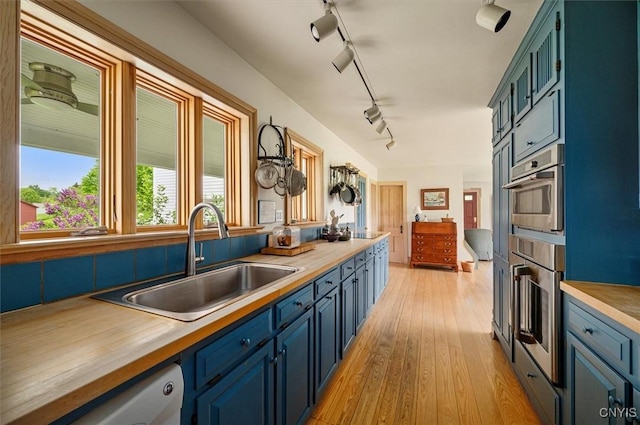 537 Earlville Rd, Hamilton, NY 13332 - kitchen featuring a sink, rail lighting, light wood finished floors, wood counters, and blue cabinets