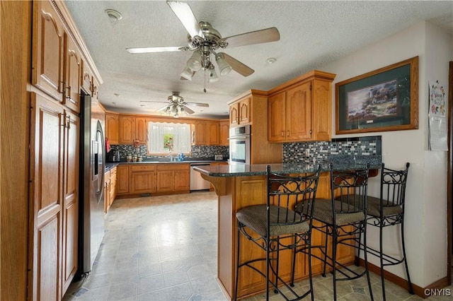 9748-9736 Podunk Rd, Lee, NY 13363 - kitchen with appliances with stainless steel finishes, a peninsula, ceiling fan, decorative backsplash, and a textured ceiling