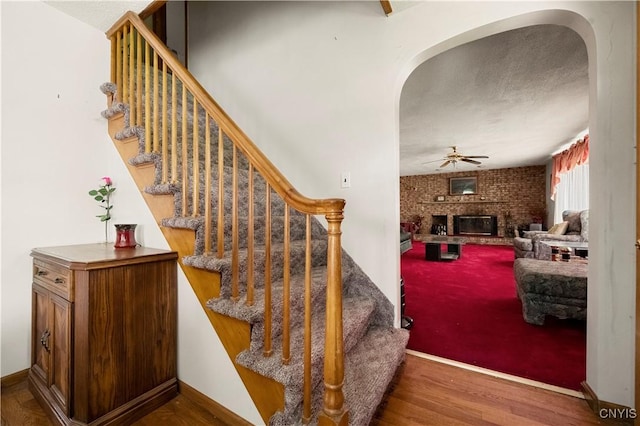 9748-9736 Podunk Rd, Lee, NY 13363 - stairs with arched walkways, a fireplace, wood finished floors, and a ceiling fan