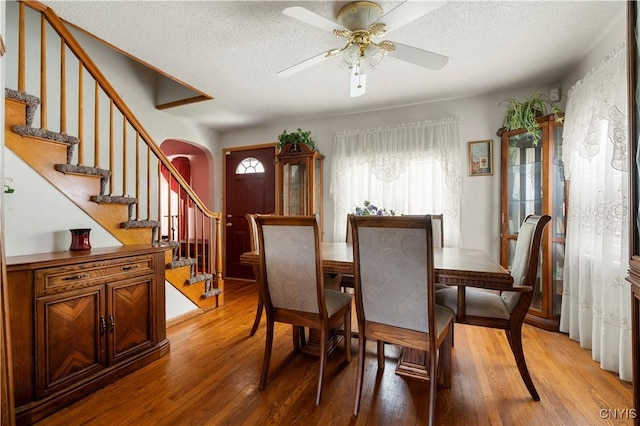 9748-9736 Podunk Rd, Lee, NY 13363 - dining area with light wood-style flooring, arched walkways, a textured ceiling, and stairs