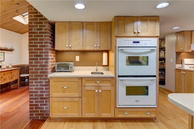 161 Bell Hill Rd, New Lisbon, NY 13342 - kitchen with white double oven, light wood finished floors, light countertops, a sink, and a skylight