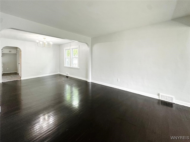 169 Davidson Ave, Buffalo, NY 14215 - empty room with arched walkways, a chandelier, dark wood-style flooring, and baseboards