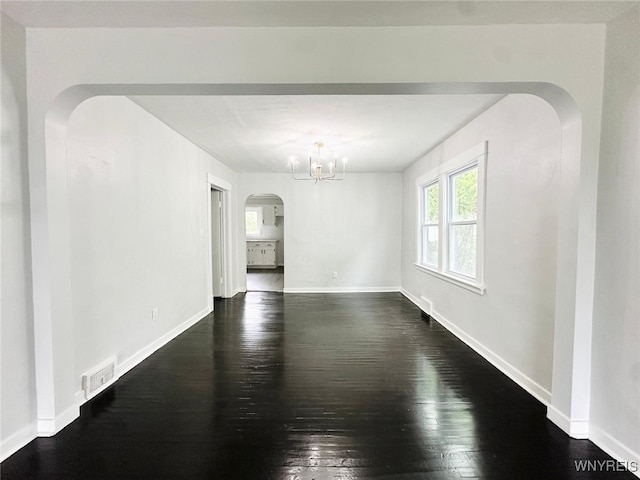 169 Davidson Ave, Buffalo, NY 14215 - empty room featuring dark wood-type flooring, arched walkways, a chandelier, and baseboards