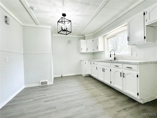 169 Davidson Ave, Buffalo, NY 14215 - kitchen featuring brick wall, a sink, white cabinets, light countertops, and light wood-style flooring