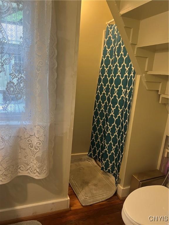 6265 Haslauer Rd, Stockbridge, NY 13409 - full bath with wood finished floors, a shower with curtain, toilet, and baseboards