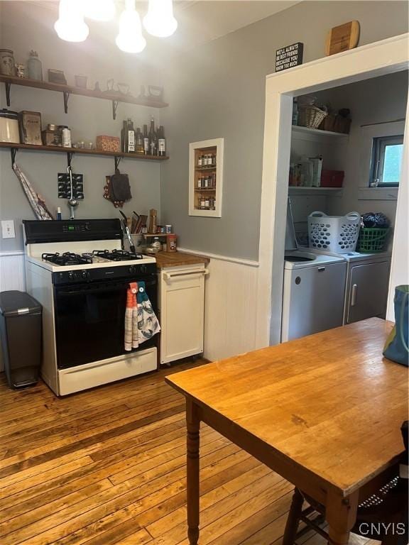 6265 Haslauer Rd, Stockbridge, NY 13409 - kitchen featuring range with gas stovetop, independent washer and dryer, a wainscoted wall, hardwood / wood-style flooring, and white cabinetry