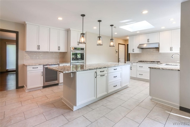 126 Crestwood Ln, Amherst, NY 14221 - kitchen featuring under cabinet range hood, a skylight, decorative backsplash, a sink, and recessed lighting