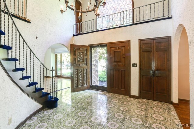 126 Crestwood Ln, Amherst, NY 14221 - entryway with arched walkways, a high ceiling, a textured wall, a chandelier, and stairs
