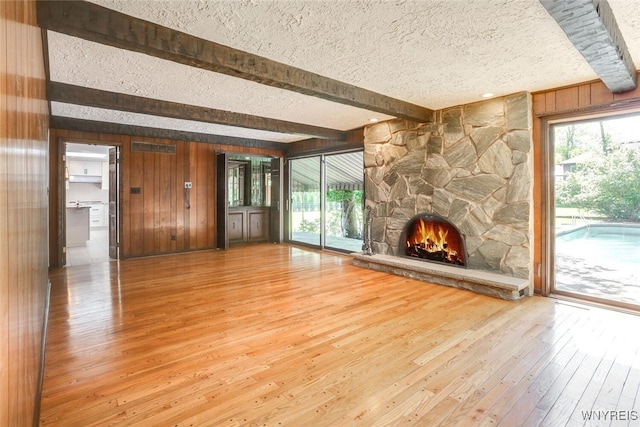 126 Crestwood Ln, Amherst, NY 14221 - unfurnished living room with beam ceiling, a textured ceiling, hardwood / wood-style flooring, wood walls, and a fireplace