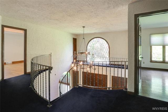 126 Crestwood Ln, Amherst, NY 14221 - hallway featuring a textured wall, an upstairs landing, a textured ceiling, a chandelier, and plenty of natural light