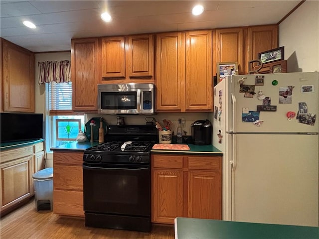 21 Curtis Rd, Hamilton, PA 16333 - kitchen with freestanding refrigerator, stainless steel microwave, black range with gas stovetop, light wood-type flooring, and brown cabinetry