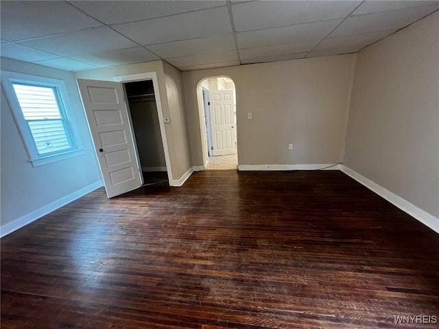 228 Weiss St, Buffalo, NY 14206 - unfurnished bedroom with arched walkways, a drop ceiling, dark wood-style floors, and baseboards