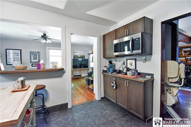 8 Terrace St, Westfield, NY 14787 - kitchen with stainless steel microwave, dark brown cabinetry, ceiling fan, dark tile patterned floors, and baseboards