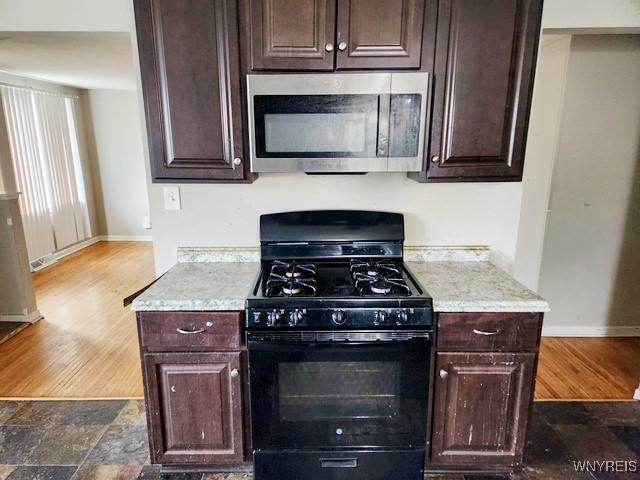 146 Lou Ann Dr, Cheektowaga, NY 14043 - kitchen with stainless steel microwave, black range with gas stovetop, dark brown cabinets, and wood finished floors