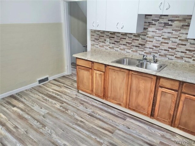199 Berkshire Ave, Buffalo, NY 14215 - kitchen featuring a sink, light wood-style flooring, brown cabinets, tasteful backsplash, and baseboards