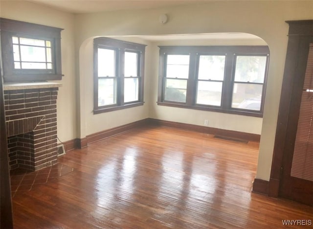 11 Verdun Ave, Buffalo, NY 14214 - unfurnished living room with arched walkways, baseboards, wood finished floors, and a fireplace with flush hearth