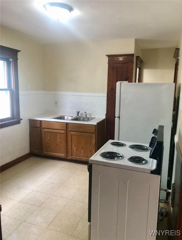 11 Verdun Ave, Buffalo, NY 14214 - kitchen with white appliances, a sink, brown cabinets, light countertops, and wainscoting