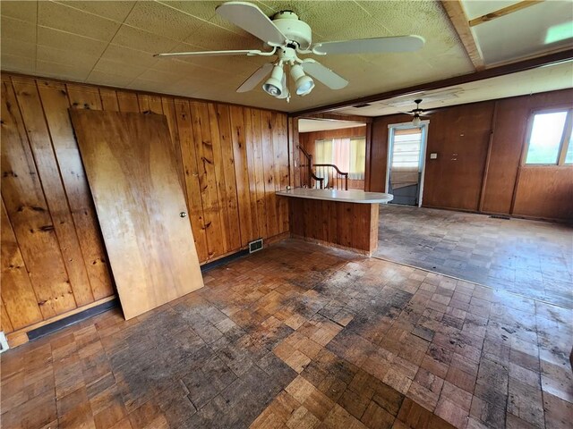 98 Gardeau St, Perry, NY 14530 - kitchen with a peninsula, wooden walls, a ceiling fan, and brown cabinetry