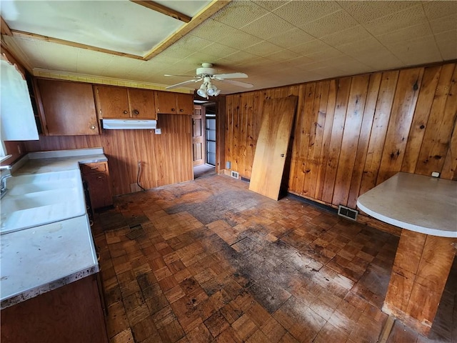 98 Gardeau St, Perry, NY 14530 - kitchen with under cabinet range hood, brown cabinets, a ceiling fan, wooden walls, and light countertops