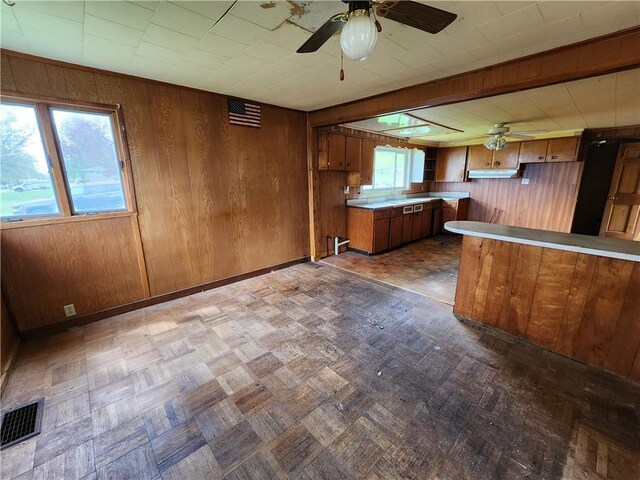 98 Gardeau St, Perry, NY 14530 - kitchen with a ceiling fan, brown cabinets, wood walls, light countertops, and healthy amount of natural light