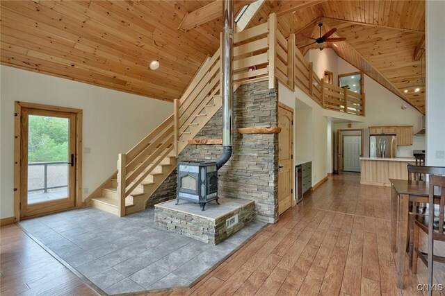 20172 Blue Heron Ln, Alexandria, NY 13607 - unfurnished living room featuring light wood-style floors, wood ceiling with exposed beams, a wood stove, stairway, and high vaulted ceiling