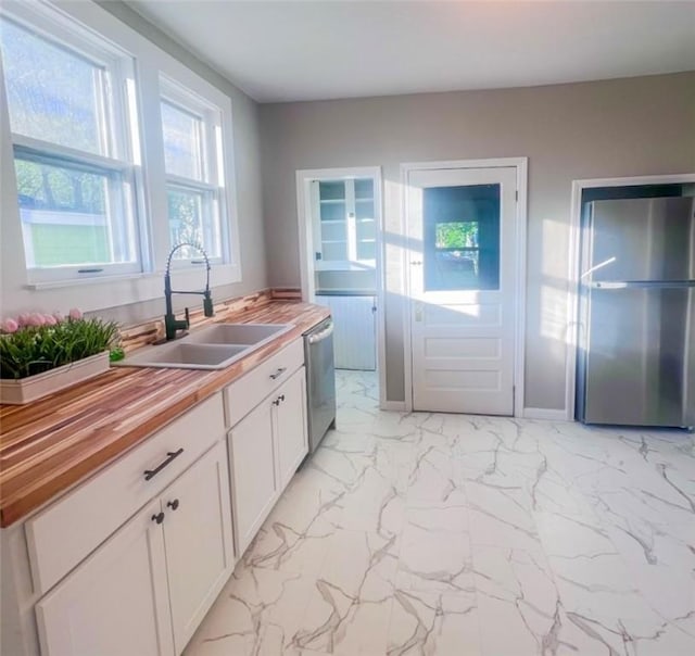 561 Post St, Elmira-City, NY 14904 - kitchen with a sink, wood counters, stainless steel dishwasher, light marble finish flooring, and white cabinetry