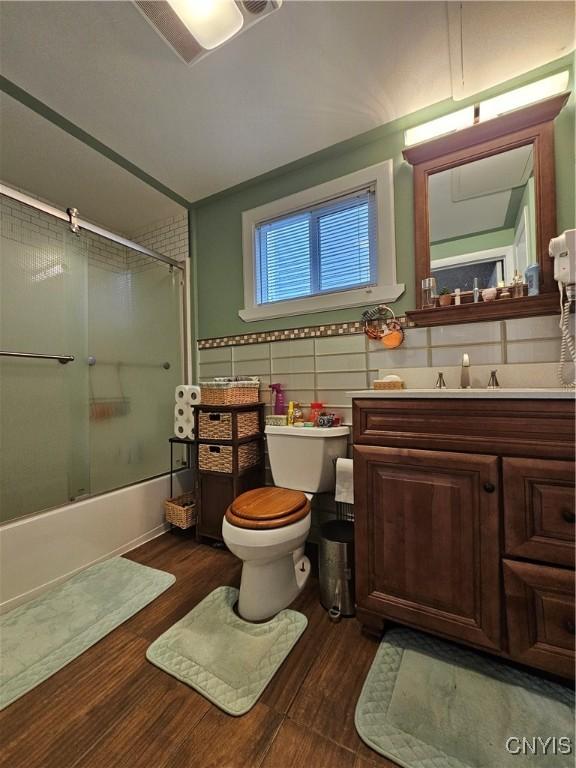 1202 Mary St, Utica, NY 13501 - full bath with bath / shower combo with glass door, vanity, toilet, wood finished floors, and tile walls
