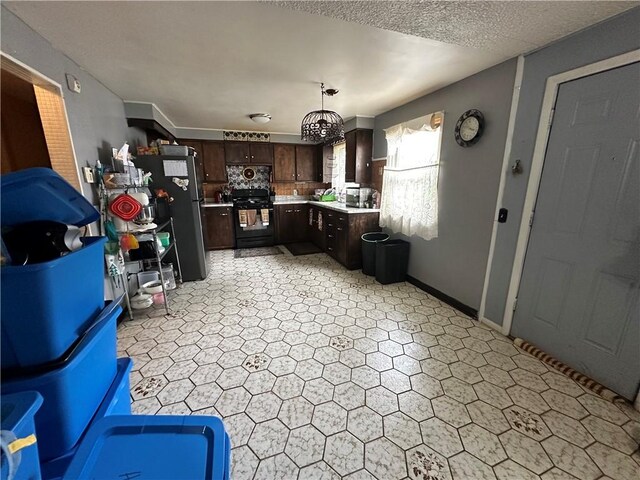 104 Newcomb St, Rochester, NY 14609 - kitchen with dark brown cabinetry, light countertops, black gas stove, and freestanding refrigerator