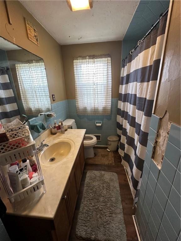 104 Newcomb St, Rochester, NY 14609 - full bathroom featuring tile walls, toilet, vanity, wainscoting, and wood finished floors