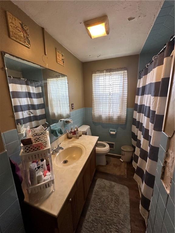 104 Newcomb St, Rochester, NY 14609 - bathroom featuring tile walls, toilet, a wainscoted wall, vanity, and a shower with curtain