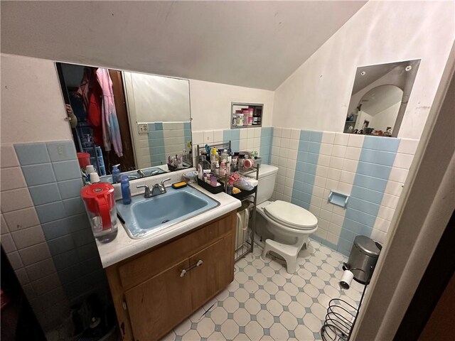 104 Newcomb St, Rochester, NY 14609 - bathroom with tile walls, lofted ceiling, toilet, a wainscoted wall, and vanity