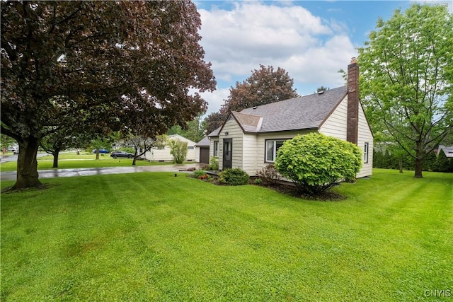 114 E Dauenhauer St, Manlius, NY 13057 - view of side of home featuring a lawn, roof with shingles, a chimney, and a garage
