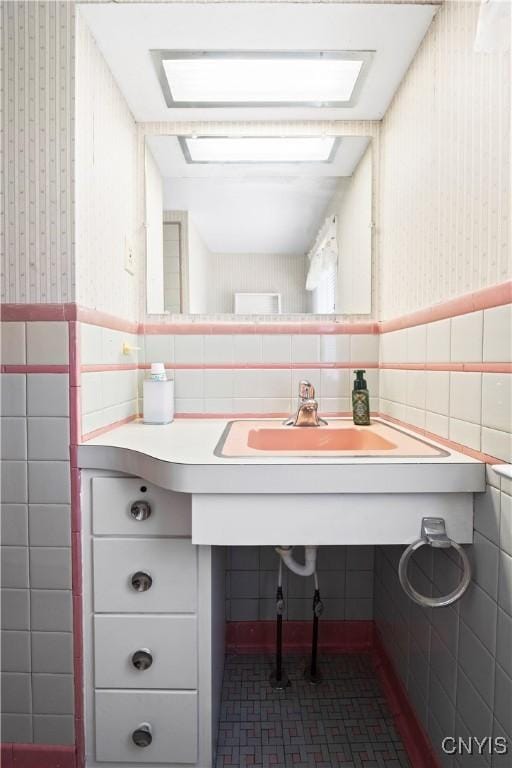 114 E Dauenhauer St, Manlius, NY 13057 - bathroom with a skylight, wallpapered walls, tile walls, a wainscoted wall, and a sink