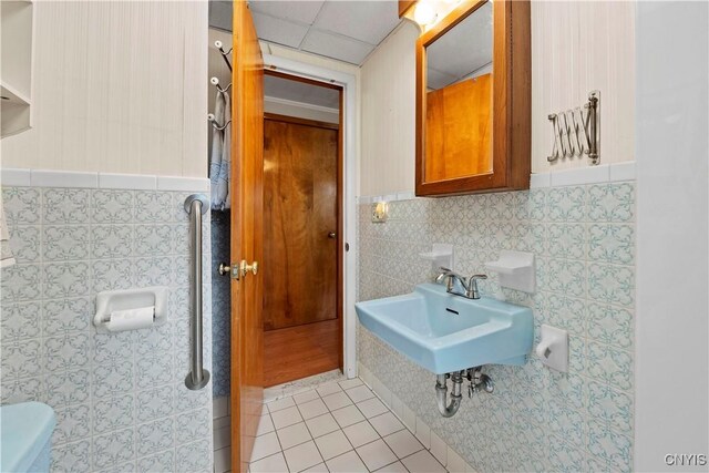 114 E Dauenhauer St, Manlius, NY 13057 - bathroom featuring tile walls, tile patterned floors, toilet, a sink, and a paneled ceiling