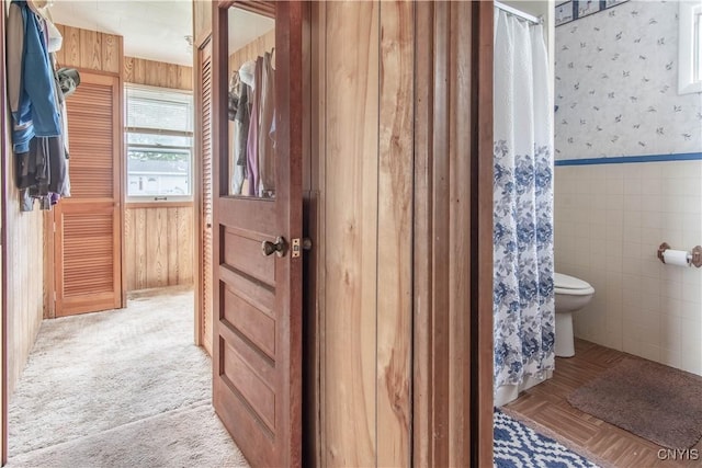 2510 Ponds Shore Dr, Cape Vincent, NY 13618 - bathroom featuring wallpapered walls, toilet, a wainscoted wall, tile walls, and a shower with shower curtain