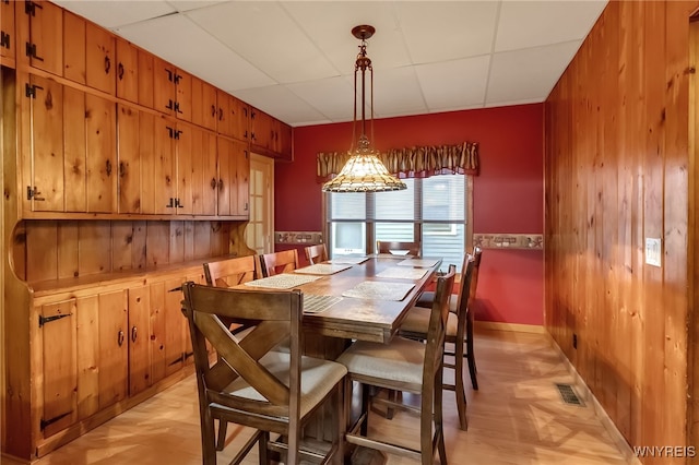 18 Spruce St, Lockport-City, NY 14094 - dining room featuring baseboards, a paneled ceiling, wooden walls, and a chandelier