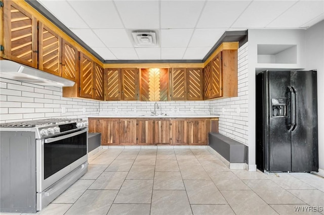 12353 Planck Rd, Perrysburg, NY 14129 - kitchen featuring black fridge, range with gas stovetop, brown cabinetry, under cabinet range hood, and backsplash