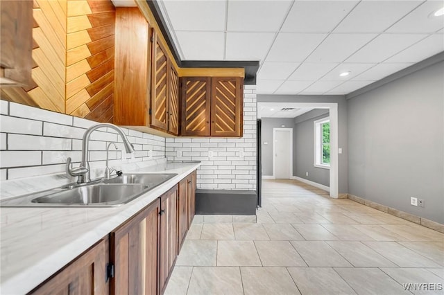 12353 Planck Rd, Perrysburg, NY 14129 - kitchen with a sink, brown cabinetry, tasteful backsplash, light countertops, and a paneled ceiling