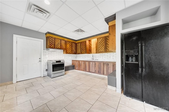 12353 Planck Rd, Perrysburg, NY 14129 - kitchen with gas stove, black fridge, a sink, brown cabinetry, and a drop ceiling