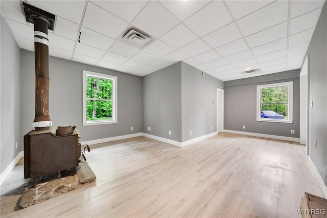 12353 Planck Rd, Perrysburg, NY 14129 - unfurnished living room featuring a wood stove, a drop ceiling, light wood-type flooring, and healthy amount of natural light