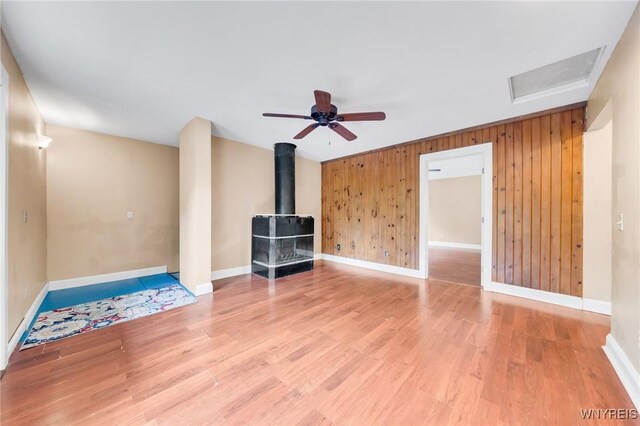 12353 Planck Rd, Perrysburg, NY 14129 - unfurnished living room featuring a wood stove, baseboards, light wood-type flooring, and wood walls