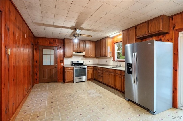 4064 Kayuta Ter, Forestport, NY 13438 - kitchen featuring stainless steel appliances, under cabinet range hood, wooden walls, a sink, and brown cabinets