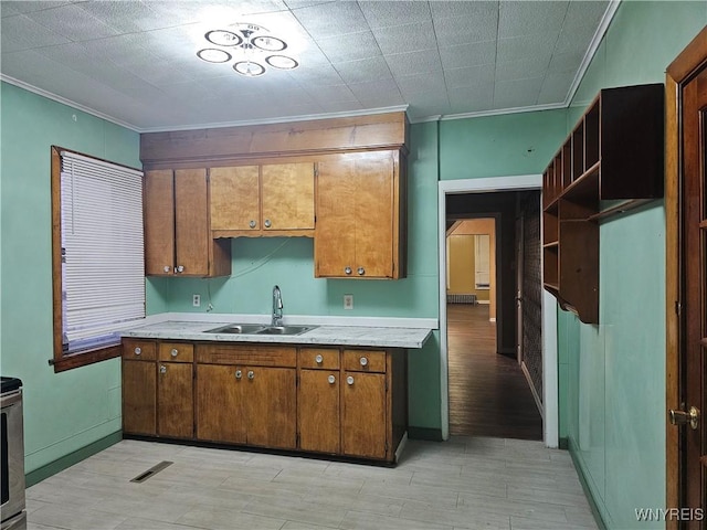2207 Linwood Ave, Niagara Falls, NY 14305 - kitchen with a sink, crown molding, light countertops, brown cabinetry, and baseboards
