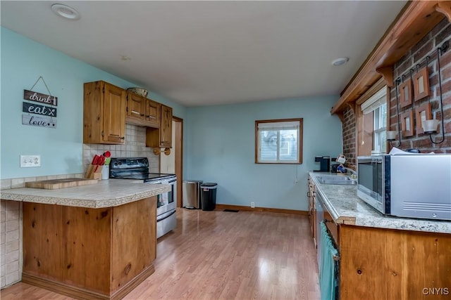 163 Maple St, Le Ray, NY 13612 - kitchen with appliances with stainless steel finishes, brown cabinetry, light wood-style flooring, light countertops, and decorative backsplash