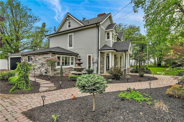 1225 W Arnold Dr, Hamburg, NY 14085 - back of property featuring an attached garage, stone siding, a chimney, and roof with shingles