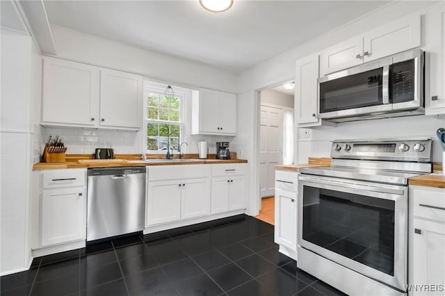 5024 Callan Dr, Lewiston, NY 14092 - kitchen with stainless steel appliances, wood counters, a sink, white cabinetry, and dark tile patterned floors