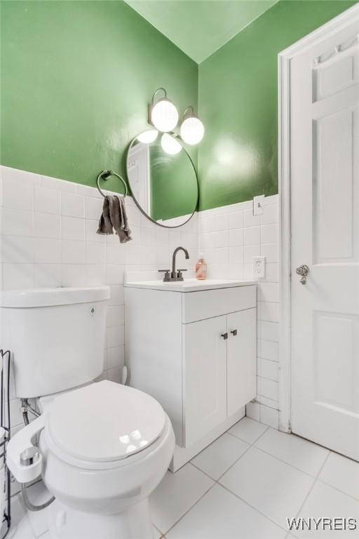 5024 Callan Dr, Lewiston, NY 14092 - half bathroom featuring tile walls, vanity, toilet, tile patterned floors, and a wainscoted wall