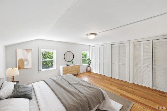 7078 Fuller Rd, Aurelius, NY 13140 - bedroom featuring two closets, wood finished floors, vaulted ceiling, and multiple windows