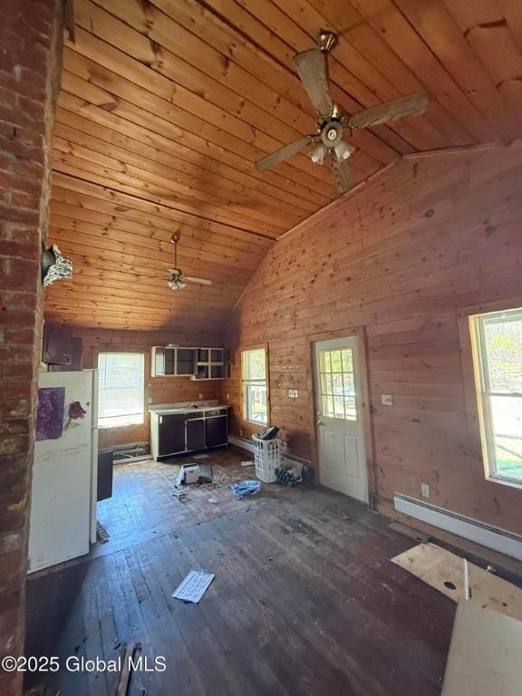 8000 State Route 8, Horicon, NY 12815 - unfurnished living room featuring a ceiling fan, healthy amount of natural light, a baseboard heating unit, wooden ceiling, and wooden walls