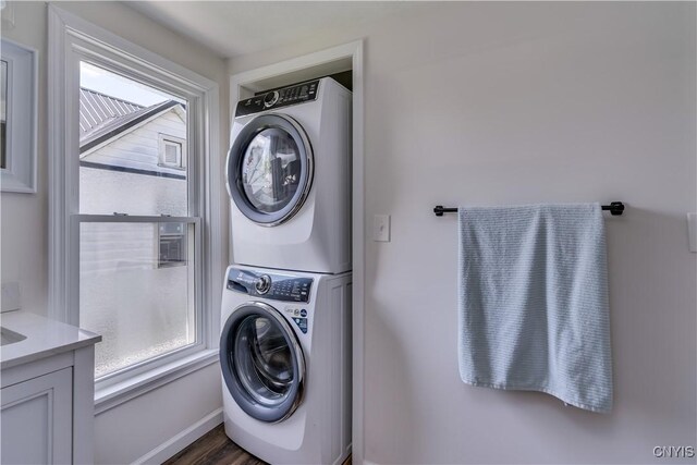 1010 Academy St, Watertown-City, NY 13601 - washroom with stacked washer / dryer, plenty of natural light, dark wood-type flooring, and baseboards